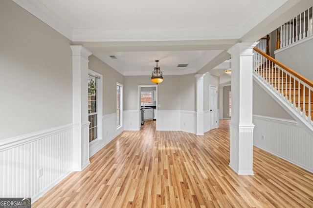 interior space with a wainscoted wall, decorative columns, stairs, and light wood-style flooring