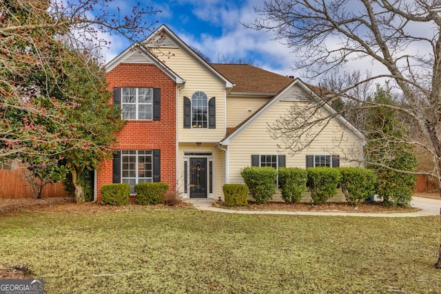 traditional home featuring brick siding, fence, and a front yard