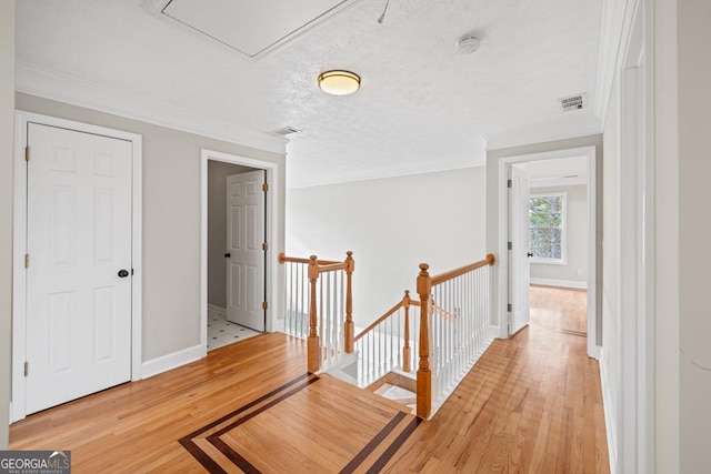 hall featuring light wood finished floors, attic access, visible vents, and an upstairs landing