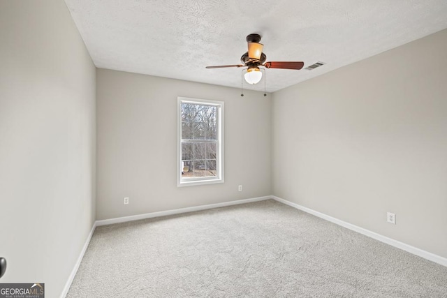 carpeted spare room featuring a textured ceiling, a ceiling fan, visible vents, and baseboards