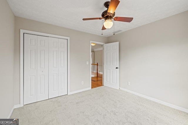 unfurnished bedroom featuring carpet floors, a closet, a ceiling fan, and baseboards