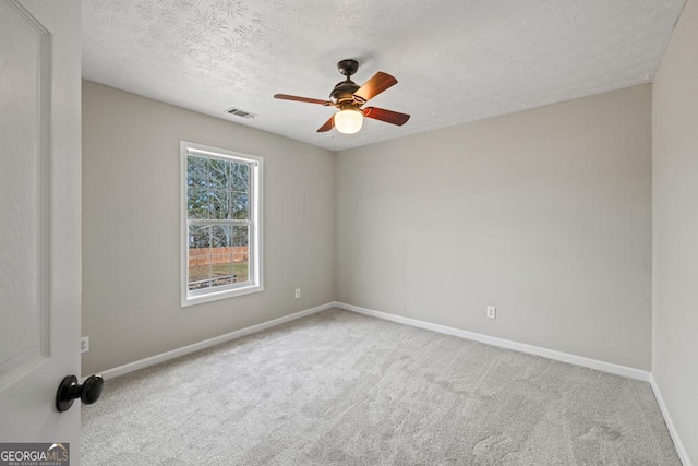 unfurnished room with a textured ceiling, carpet flooring, a ceiling fan, visible vents, and baseboards