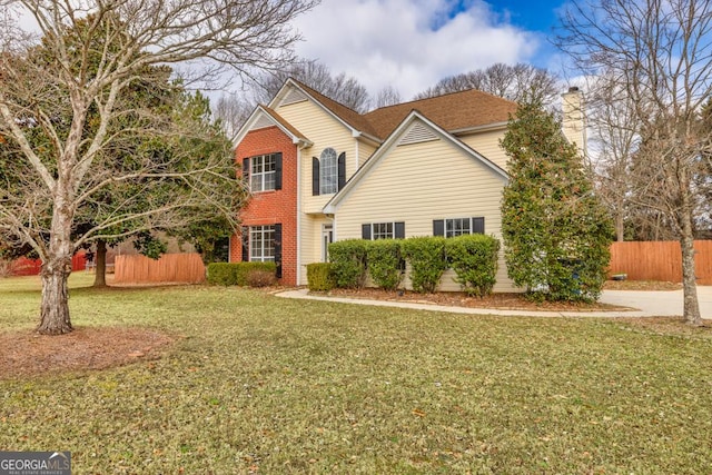 traditional home featuring fence, a front lawn, and brick siding