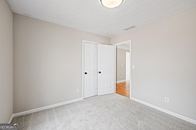 unfurnished bedroom with a closet, carpet, visible vents, and baseboards