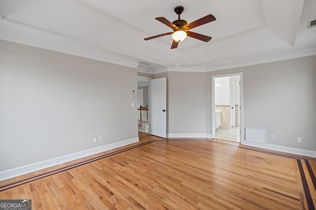 unfurnished bedroom with a tray ceiling, baseboards, visible vents, and light wood finished floors