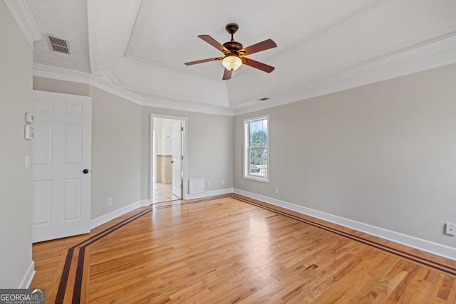 unfurnished bedroom featuring baseboards, visible vents, a raised ceiling, crown molding, and light wood-type flooring