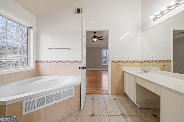 full bath with visible vents, lofted ceiling, a garden tub, tile patterned flooring, and tile walls