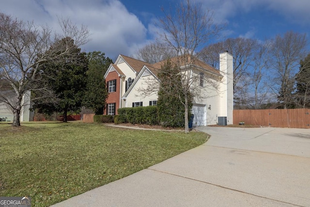 traditional-style house with a garage, fence, concrete driveway, a front lawn, and a chimney