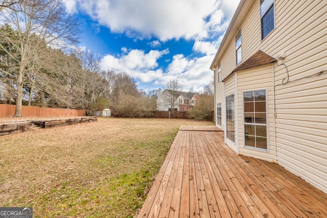 view of yard featuring a storage shed, fence, an outbuilding, and a wooden deck