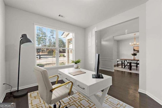 office area with dark wood-style floors, baseboards, visible vents, and an inviting chandelier