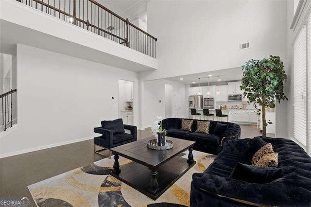 living room with baseboards, a high ceiling, and visible vents