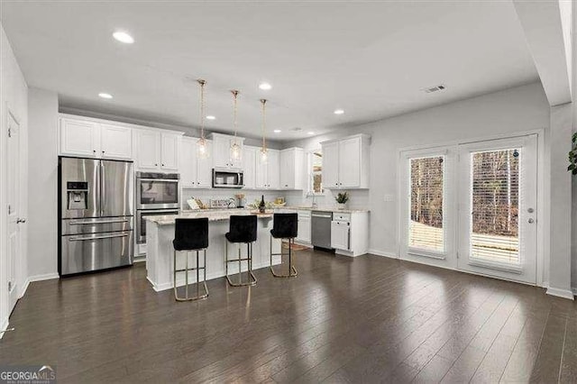 kitchen with a kitchen island, stainless steel appliances, light countertops, white cabinetry, and pendant lighting