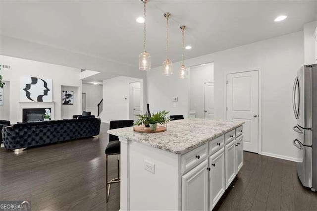 kitchen featuring a center island, pendant lighting, freestanding refrigerator, open floor plan, and white cabinetry