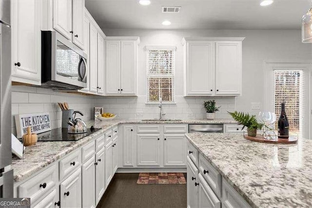 kitchen with stainless steel appliances, a sink, visible vents, and white cabinets