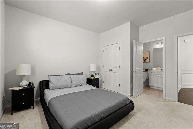 bedroom featuring light carpet, a closet, connected bathroom, and baseboards