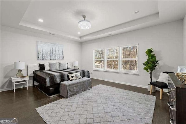 bedroom with dark wood-style floors, a raised ceiling, and baseboards