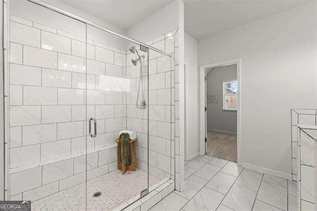 bathroom with marble finish floor, a shower stall, and baseboards