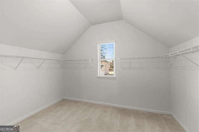 spacious closet with light colored carpet and vaulted ceiling