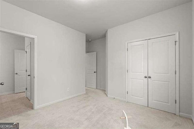 unfurnished bedroom with a closet, light carpet, and baseboards