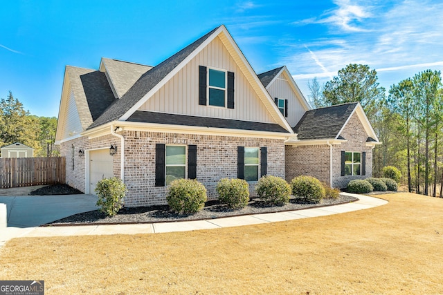 view of front of house with a shingled roof, brick siding, and fence