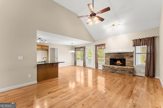 unfurnished living room featuring plenty of natural light, light wood-style flooring, a fireplace, and ceiling fan