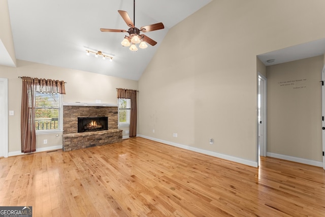 unfurnished living room with baseboards, a ceiling fan, light wood-style floors, a fireplace, and high vaulted ceiling