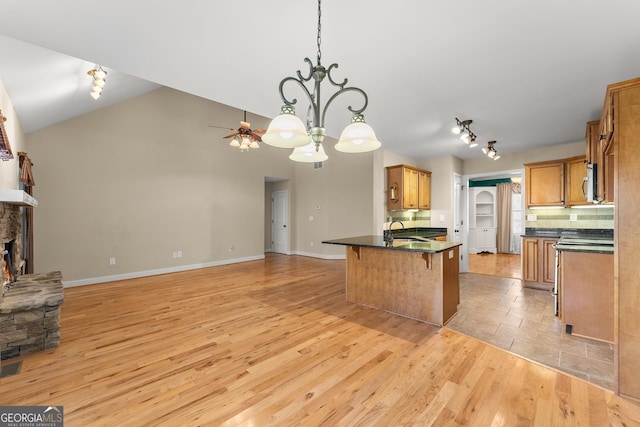 kitchen with dark countertops, brown cabinets, open floor plan, a fireplace, and a sink