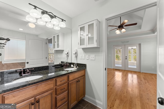 bathroom with french doors, a raised ceiling, a sink, and double vanity