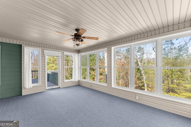 unfurnished sunroom featuring a healthy amount of sunlight, wooden ceiling, and ceiling fan