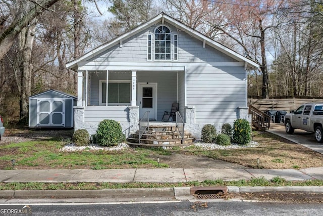 bungalow-style home featuring a storage unit, a porch, and an outdoor structure