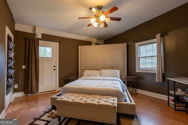 bedroom with lofted ceiling, multiple windows, wood finished floors, and baseboards