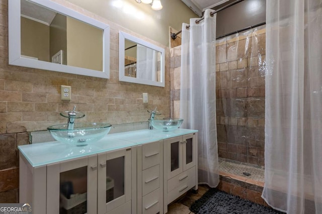 bathroom featuring a stall shower, a sink, decorative backsplash, and double vanity