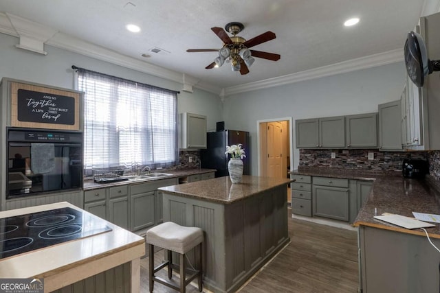 kitchen featuring black appliances, ornamental molding, and a center island