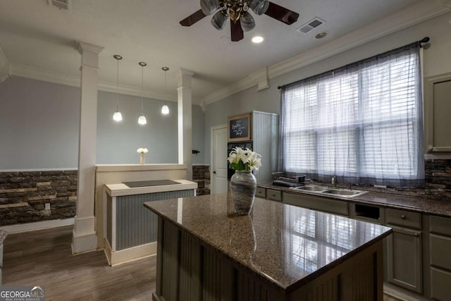 kitchen with decorative light fixtures, a sink, visible vents, dark stone countertops, and decorative columns