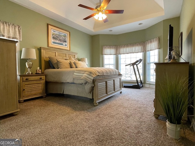 bedroom with carpet floors, ceiling fan, and a tray ceiling