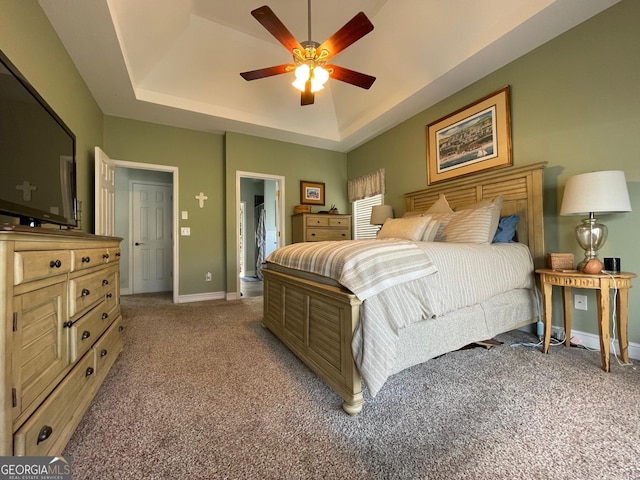 bedroom with a ceiling fan, a raised ceiling, carpet flooring, and baseboards