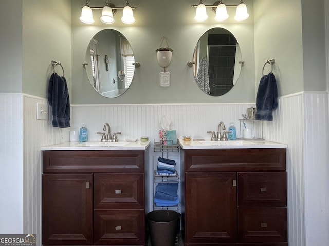 bathroom with a wainscoted wall, two vanities, and a sink