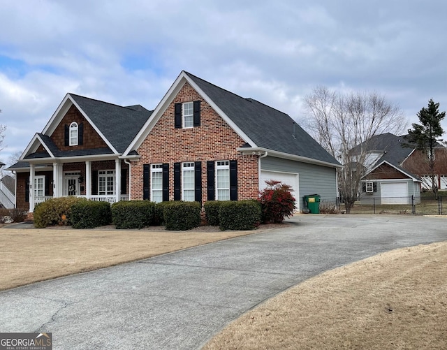 view of front of property with a garage, aphalt driveway, covered porch, fence, and brick siding