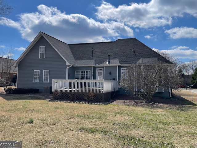 view of front of house featuring roof with shingles, a front yard, and a wooden deck