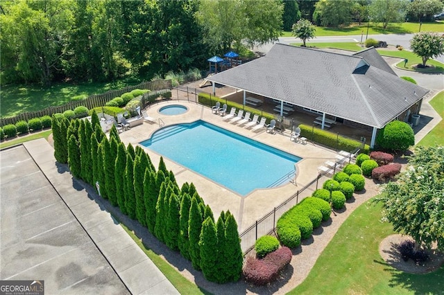 pool with a patio area, fence, and a hot tub