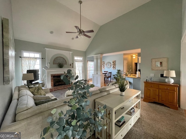 carpeted living room with high vaulted ceiling, a fireplace, decorative columns, and a ceiling fan