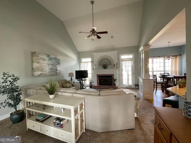 living room featuring high vaulted ceiling, plenty of natural light, a fireplace, and ornate columns