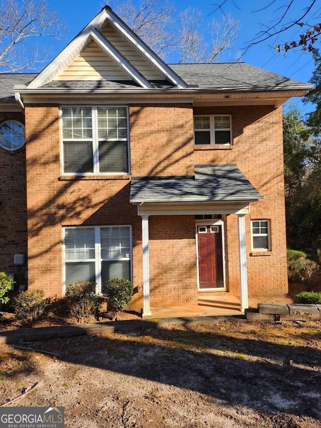 view of front of house with brick siding and roof with shingles