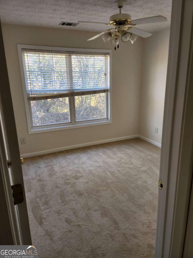 unfurnished room featuring a textured ceiling, carpet flooring, visible vents, and baseboards