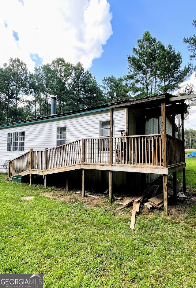 back of property featuring a deck and a lawn