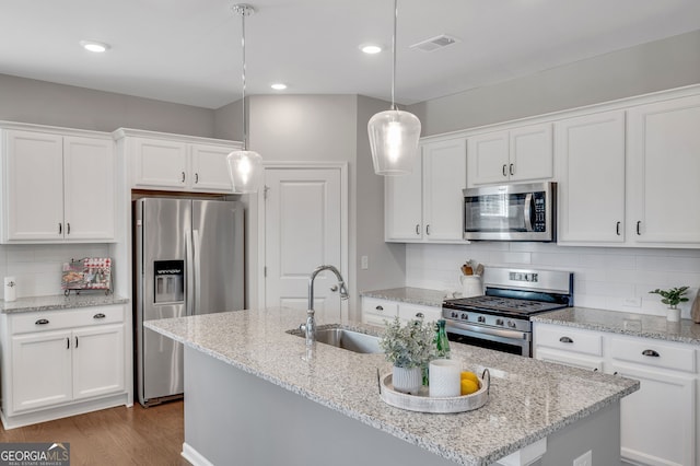 kitchen with visible vents, appliances with stainless steel finishes, white cabinets, a sink, and wood finished floors