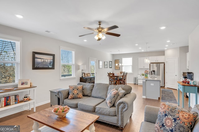 living room with light wood-style flooring, recessed lighting, visible vents, a ceiling fan, and baseboards