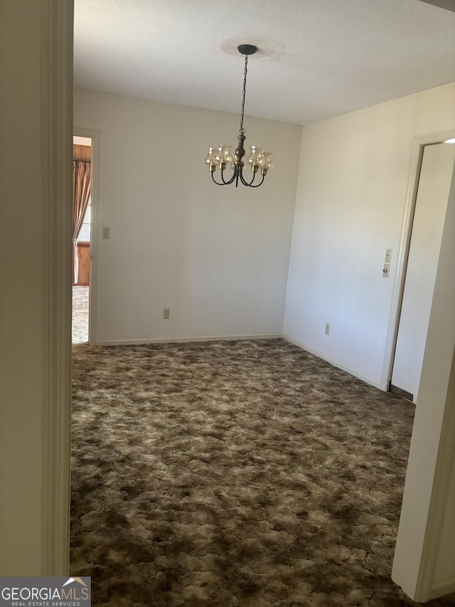 empty room featuring an inviting chandelier, baseboards, dark colored carpet, and a textured ceiling