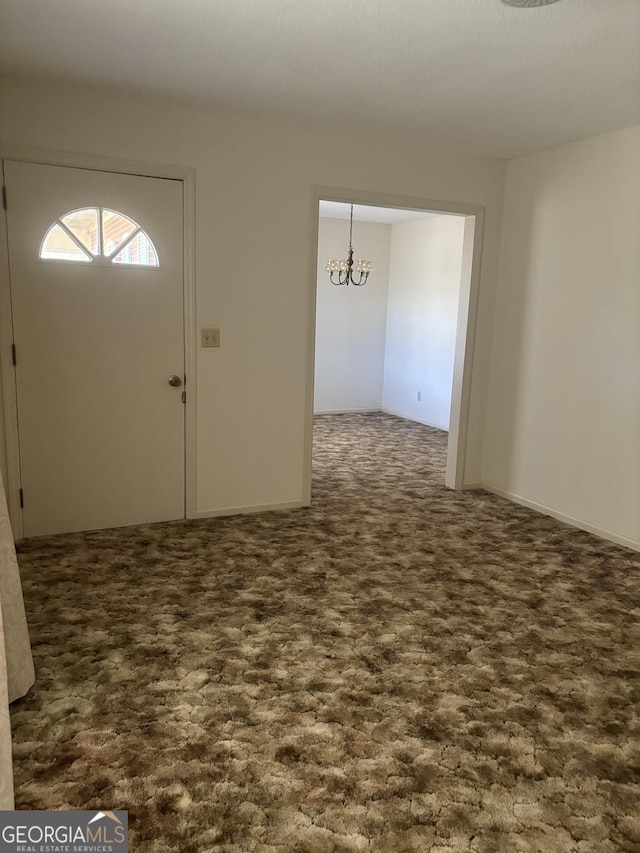 entrance foyer featuring dark carpet and a notable chandelier