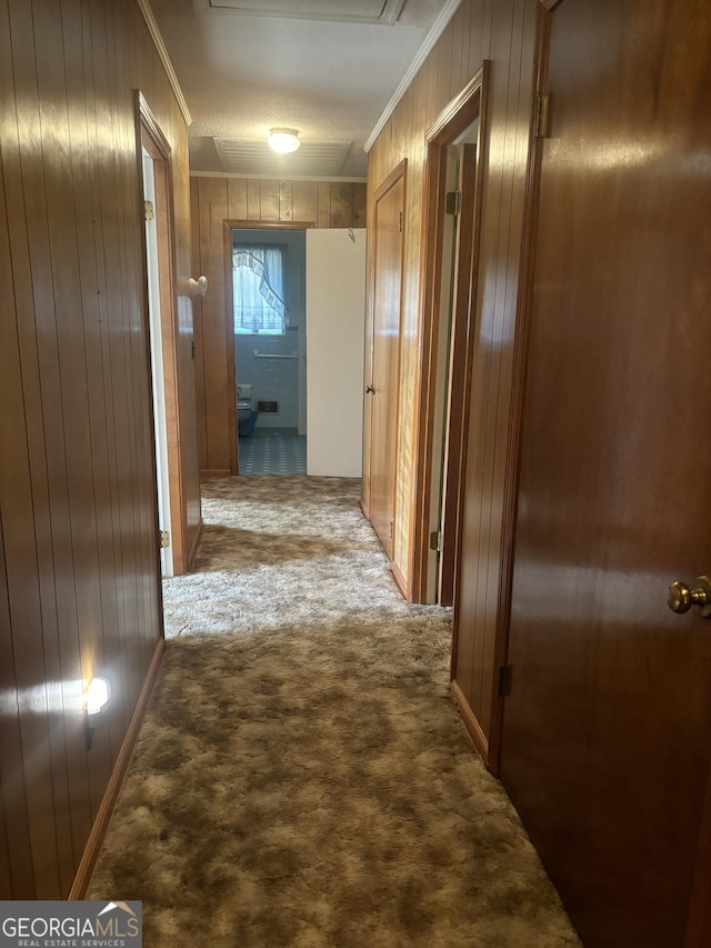 hall featuring wooden walls, ornamental molding, and carpet flooring